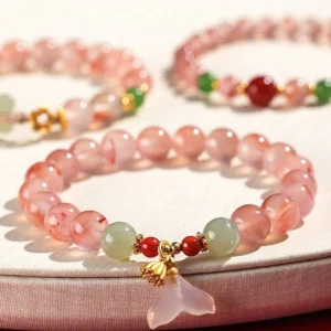 South Red Agate Hetian Jade butterfly bracelet on red fabric background, overhead view showing vibrant red agate beads with light green jade accents and gold hardware