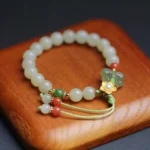 925 sterling silver jade butterfly bracelet with carved jade charm pendant and red agate on wooden background