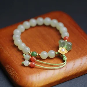 925 sterling silver jade butterfly bracelet with carved jade charm pendant and red agate on wooden background