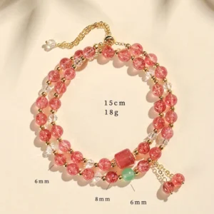 Strawberry quartz double wrap crystal healing bracelet with pink beads, gold clasp, and charm details on beige background