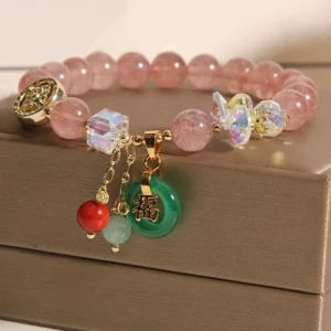 Close-up detail of strawberry quartz fu charm bracelet dangling ornaments and green fu character pendant