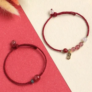Two variations of strawberry quartz healing bracelets with red string and jade or white agate beads flat lay