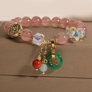 Overhead flat lay of strawberry quartz jade fu prosperity bracelet featuring pink round beads, faceted crystal accents, and hanging green jade fu pendant
