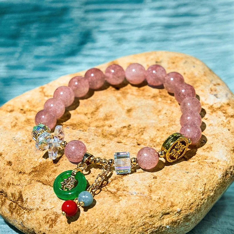 Strawberry quartz jade Fu character charm bracelet overhead flat lay on blue stone background with pink quartz beads and green jade pendant