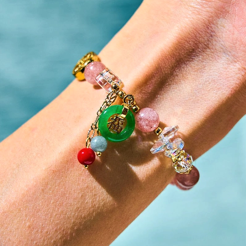 Strawberry quartz Fu charm bracelet worn on wrist close-up shot with pink beads green jade pendant and dangling tassel