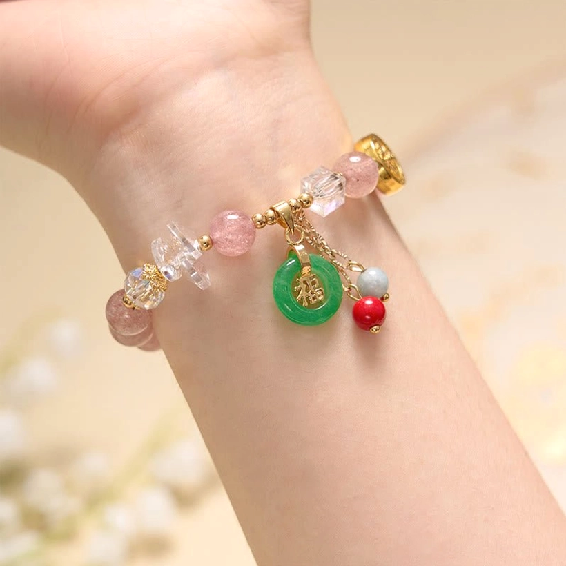 Strawberry quartz Fu charm bracelet on human wrist with floral background pink beads green jade and dangling accents