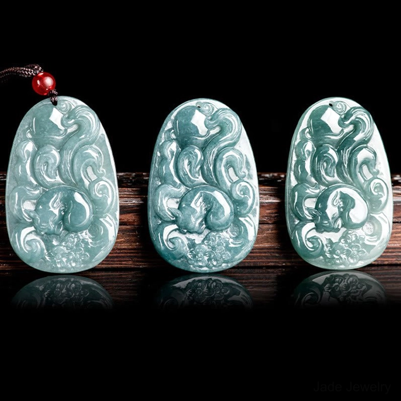Three matching nine-tailed fox jade pendants arranged together, showing consistent carving and light cyan color