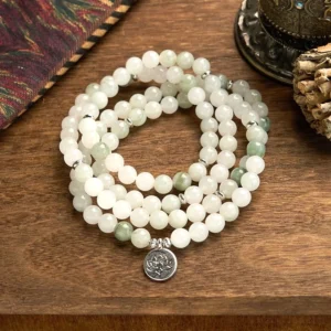 108 Tianshan jade mala bracelet with hand-engraved silver lotus charm pendant displayed on wooden surface, showcasing white and light green natural jade beads in layered meditation mala design