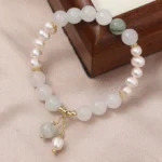 Tianshan jade and pearl abundance bracelet with gold charms, matte white jade beads, freshwater pearls, and green jade accent stone