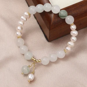 Tianshan jade and pearl abundance bracelet with gold charms, matte white jade beads, freshwater pearls, and green jade accent stone