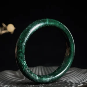Tibetan black-green jade protection bangle bracelet flat lay top view showing polished dark green jade with natural veining and smooth surface