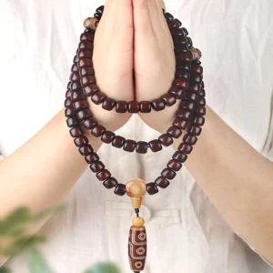 Hand-held 108 mala bead bracelet with three-eye Dzi bead, jade stones, and bodhi seeds displaying authentic Tibetan spiritual craftsmanship