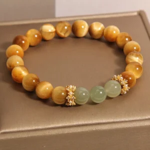 Tiger Eye and Jade courage bracelet with pearl-adorned gold spacers on brown display tray - overhead flat lay view showing warm golden tiger eye beads and pale green jade stones