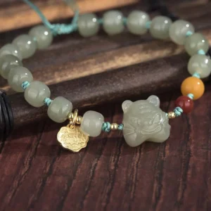 Close-up side view of Chinese zodiac tiger jade beaded bracelet showing smooth beads and carved tiger ornament detail