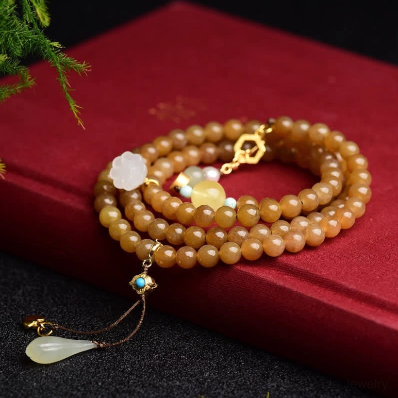 Multi-layer beaded bracelet with brown jade beads, white jade lotus charm, and turquoise accents on red satin fabric