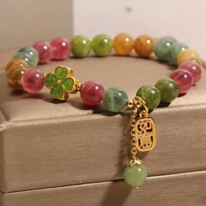 Side view of tourmaline jade lucky bracelet showing engraved Ruyi pendant on tan jewelry presentation box