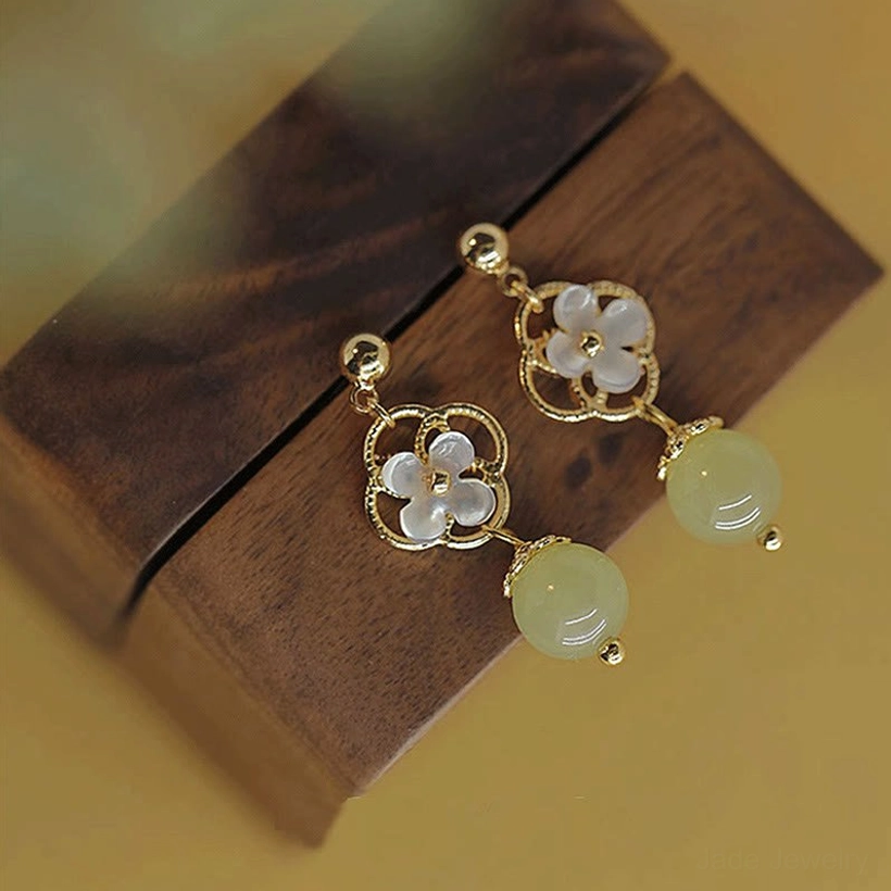 Jade flower drop earrings worn on ear, lower side close-up showing the jade bead dangling element with casual outfit styling