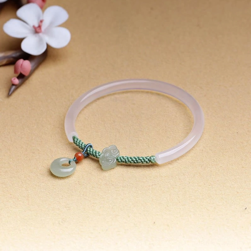 Jade peace buckle bracelet front flat lay with flower decoration, showing delicate braided fastener and complete setup