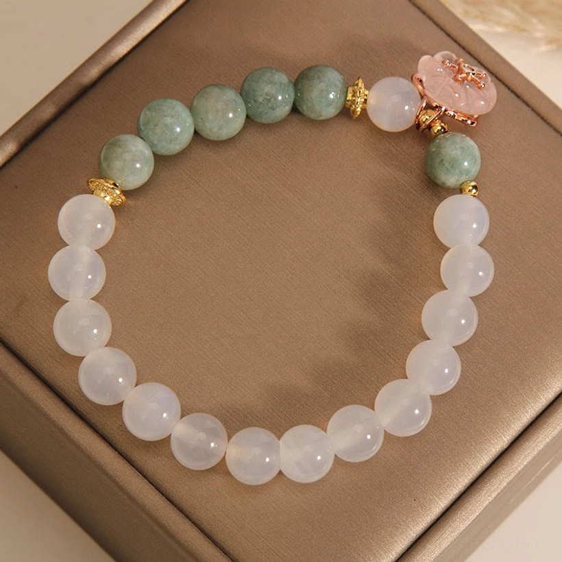 Side overhead view of jade agate flower bracelet with pink floral pendant and gold metal accents