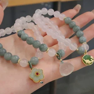 Three handmade white agate jade peace buckle lotus flower bracelets displayed flat overhead view showing all three charm variations