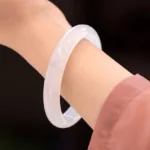 Natural white chalcedony bangle bracelet worn on wrist, close-up side view showing smooth polished translucent surface