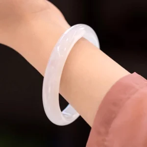 Natural white chalcedony bangle bracelet worn on wrist, close-up side view showing smooth polished translucent surface