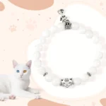 White chalcedony cat beaded bracelet with silver cat charm on pink paw print background