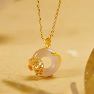 White chalcedony peace buckle butterfly pendant necklace with gold accents on warm background - top view close-up