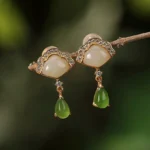 White and cyan jade fan drop earrings with gold plating on natural wooden branch