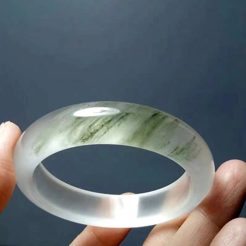 Translucent white green golden silk jade bangle showing subtle green veining on creamy white base