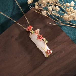 Handcrafted white jade bamboo lotus necklace showing detailed side profile with red enamel flower clusters and gold vine details