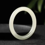 Natural white jade prosperity bangle with smooth polished finish, front view on dark background
