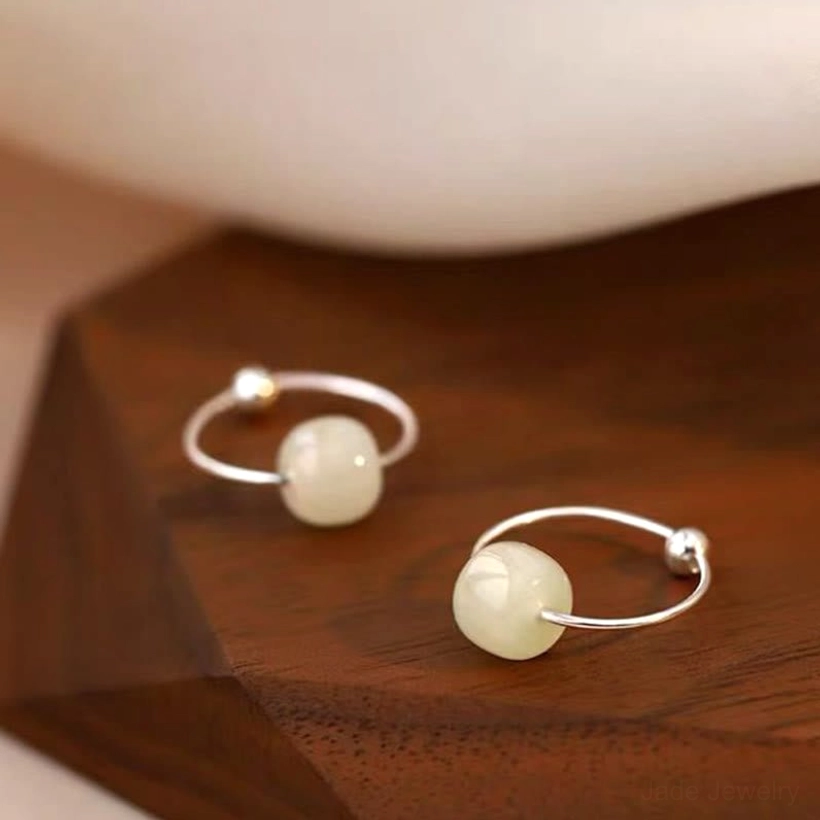White jade bead sterling silver hoop earrings - top-down flat lay featuring matte white jade beads on polished silver with wooden display base