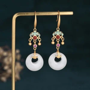 White jade blessing drop earrings with gold-tone metal and enamel accents, frontal view on display stand