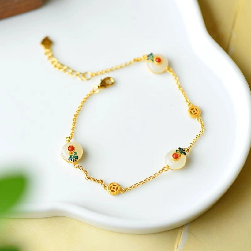 White jade luck bracelet flat lay on white ceramic tray, featuring adjustable gold chain with enamel-inlaid jade pendants and lobster clasp