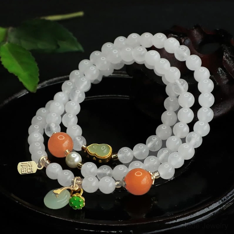 Side view of authentic white jade protective bracelet with orange beads, jade peace buckle and green gemstones on decorative wooden backdrop