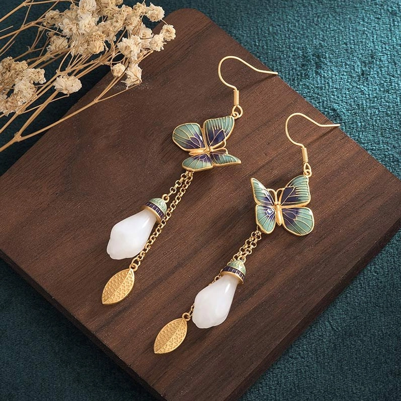 Pair of white jade butterfly drop earrings flat lay on wooden board with enamel butterfly hook detail
