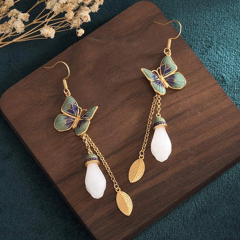 White jade butterfly earrings side view on wooden surface showing individual earring with gold leaf charm accent