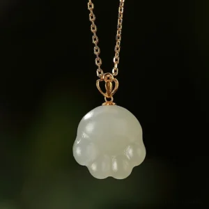 Single Hetian white jade cat paw necklace pendant with crown-style gold bail on black background close-up detail