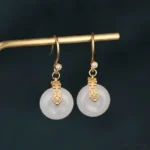 White jade double happiness fortune earrings with gold hardware close-up front view