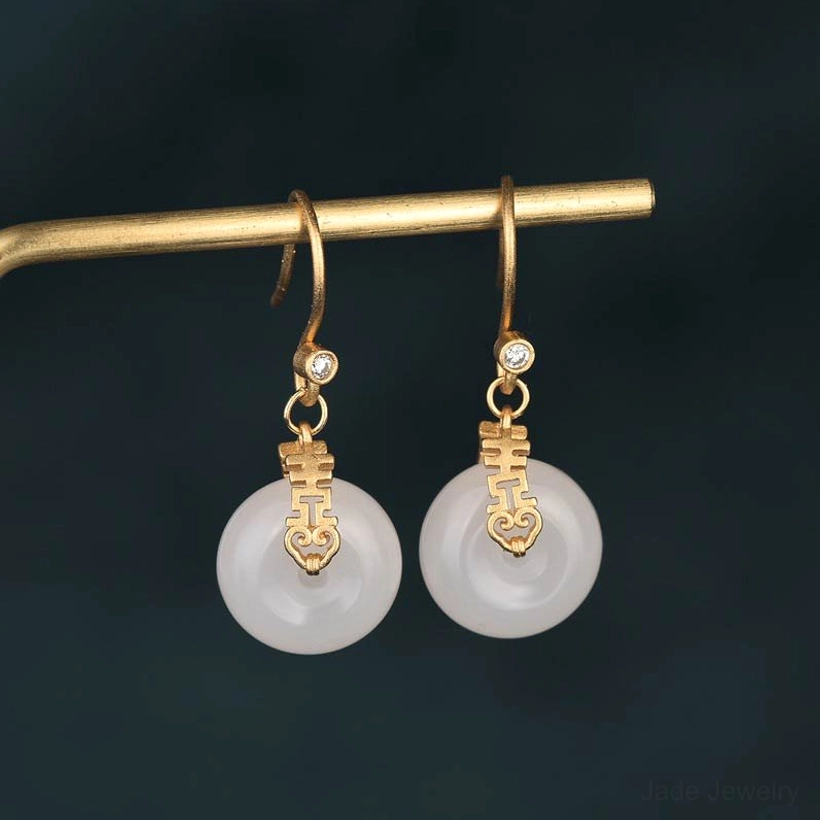 White jade double happiness fortune earrings with gold hardware close-up front view