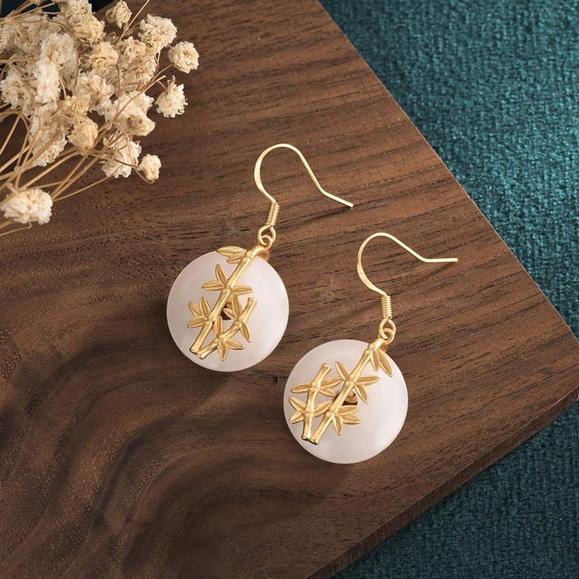 White jade earrings flat lay with wooden surface - pair of handmade jade earrings styled with natural dried flowers