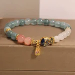 White jade koi fish prosperity bracelet with gold enamel charm in luxury jewelry gift box, front angled view