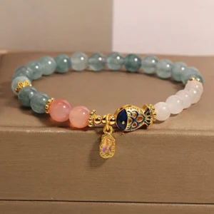 White jade koi fish prosperity bracelet with gold enamel charm in luxury jewelry gift box, front angled view