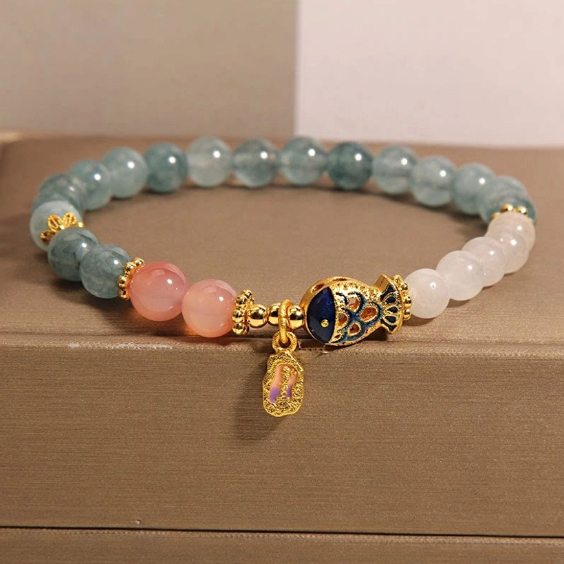 White jade koi fish prosperity bracelet with gold enamel charm in luxury jewelry gift box, front angled view