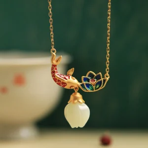 White jade koi fish lotus copper necklace pendant flat lay front view on vintage Chinese style desktop with gold-plated metal and cloisonne enamel details