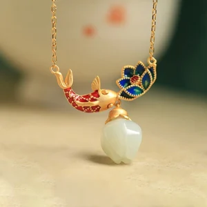 Handcrafted white jade koi fish lotus pendant necklace oblique front view showing red enamel koi blue enamel lotus and jade drop charm on light vintage table