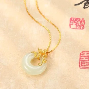 Creamy white jade pendant on fine gold chain displayed on authentic vintage Chinese calligraphy paper with red seals, emphasizing the necklace's connection to Eastern spiritual traditions