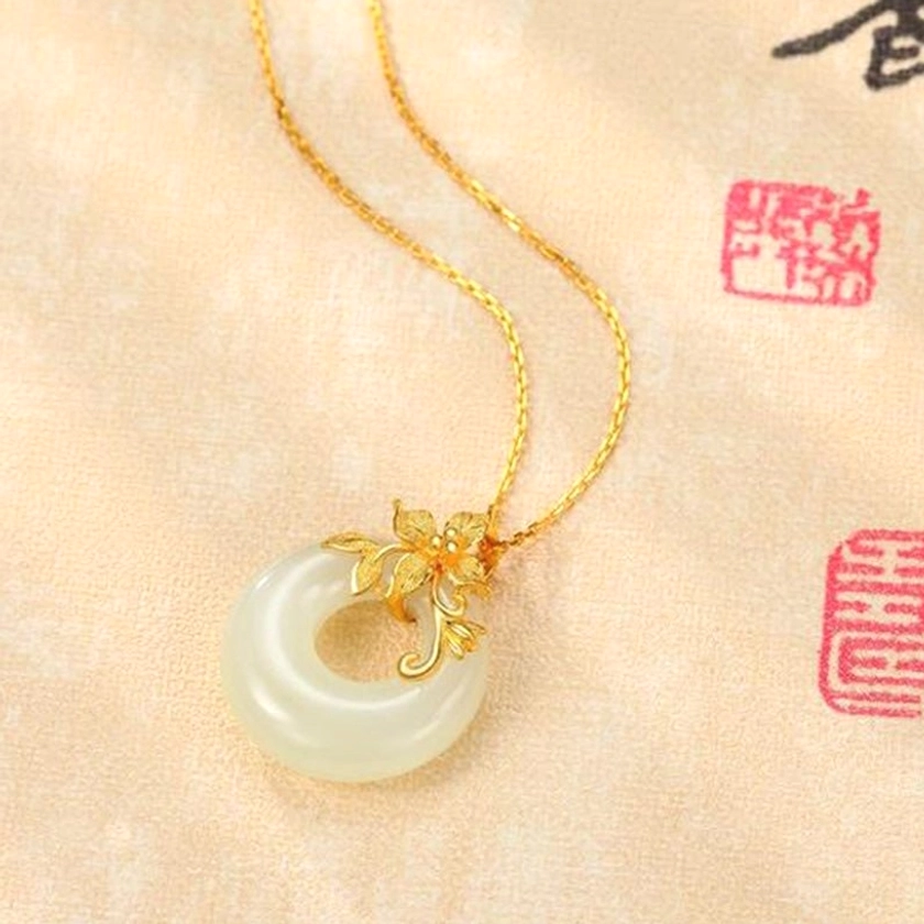 Creamy white jade pendant on fine gold chain displayed on authentic vintage Chinese calligraphy paper with red seals, emphasizing the necklace's connection to Eastern spiritual traditions