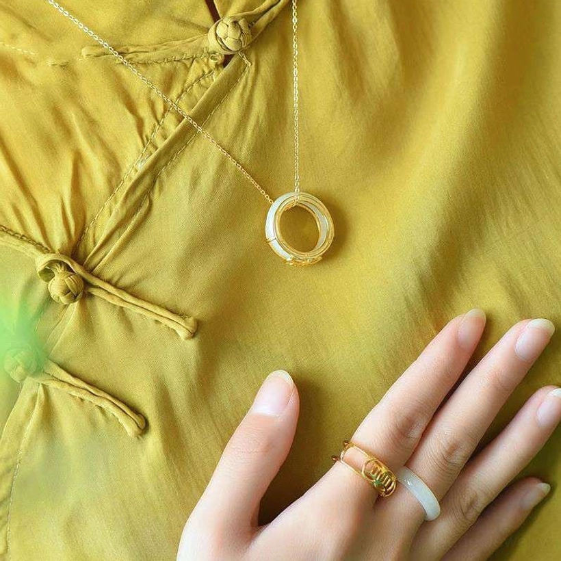 White jade ring necklace pendant worn with matching rings on hand, styled with traditional background